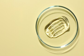 Cosmetic product in Petri dish on pale yellow background, top view. Space for text