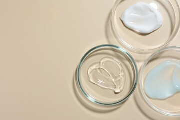 Different cosmetic products in Petri dishes on beige background, flat lay. Space for text