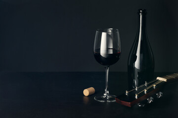 Acoustic guitar and red wine on black table. Space for text
