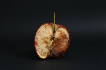 Half of spoiled apple on black background