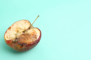 Half of spoiled apple on turquoise background. Space for text