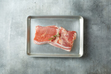 A top down view of a stack of raw bacon on a baking sheet.