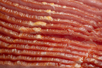 A closeup view of a stack of bacon strips, as a background.