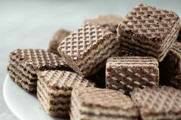 A closeup view of a pile of chocolate wafer cookies, on a plate.