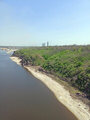View from the Arch Bridge on the calm water surface of the Dnieper that washes the sandy shores and rocky cliffs of Khortytsia Island.