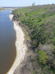 View from the Arch Bridge on the calm water surface of the Dnieper that washes the sandy shores and rocky cliffs of Khortytsia Island.