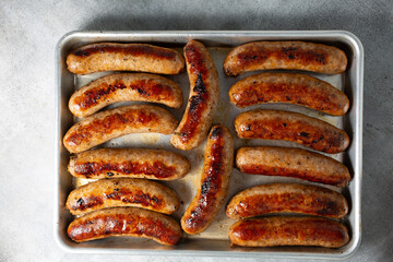 italian sausaA top down view of several cooked Italian sausages, on a baking sheet.ge