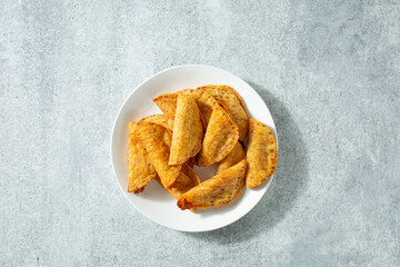 A top down view of a pile of mini tacos, on a plate.