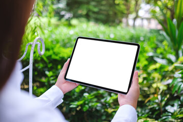 Mockup image of a woman holding digital tablet with blank white desktop screen in the nature...