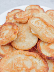 Small pancakes forming a delicious golden mountain on white plate