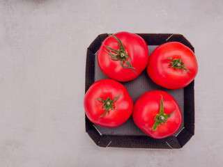 Fresh red tomatoes in black cardboard container copy space