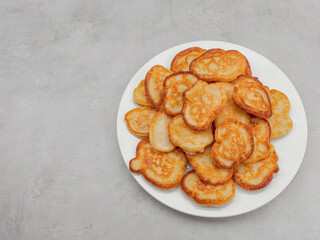 Delicious golden pancakes stacked on white plate copy space