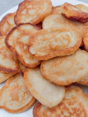 Golden brown pancakes stacked on white plate