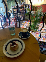 Cozy coffee break in a bookstore cafe with a dessert and cappuccino on a wooden table overlooking...