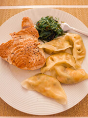 Grilled tuna steak, gyoza dumplings and seaweed salad composing a healthy meal