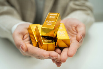 Asian woman holding gold bar in finance business.