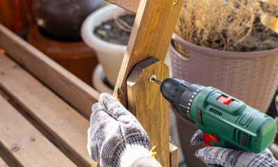 A worker in gloves uses a cordless screwdriver in the household. Cordless drill-screwdriver....