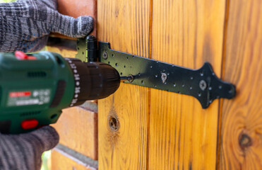 A worker in gloves uses a cordless screwdriver in the household. Cordless drill-screwdriver....
