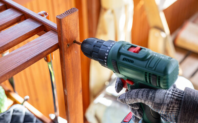 Screwing screws using an electric screwdriver. Assembling furniture using a cordless...