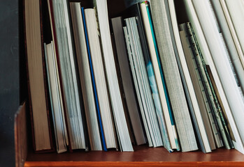 Books on library shelves with visible section markers. Some volumes on a table in front of blurred...