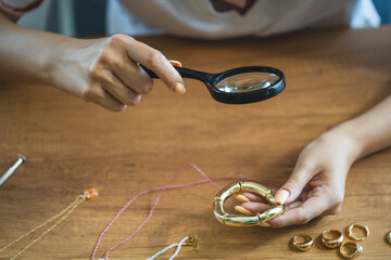 craftswoman hand look at bracelet through a magnifying glass