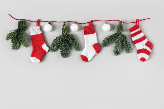 Christmas festive garland of white balls, Christmas tree branches and knitted decorative red socks Santa Claus. Winter knitting creativity