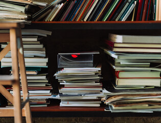 Boy placing a book on a high shelf using a small stool in a library setting. Learning and...