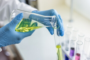 Scientist pouring liquid on test tube at laboratory. Attentive person wearing protective uniform...