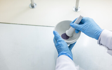 A chemist grinds reagents in a mortar. Preparing a reagent for laboratory testing.