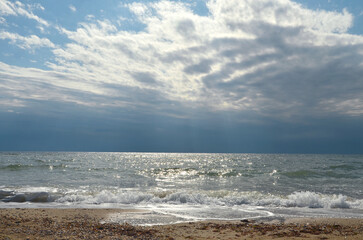 Seashore with waves hitting the shore and white clouds in the blue sky. Waves on the beach in the morning  Summer vacation near the sea  concept.