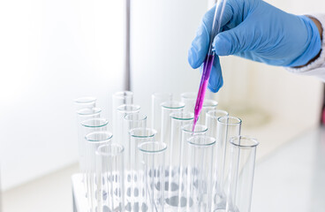 Scientist dripping color liquid into test tube in laboratory. Pipette with a drop and scientific...