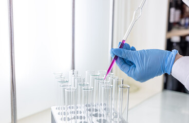 Scientist dripping color liquid into test tube in laboratory. Pipette with a drop and scientific...