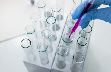 Scientist dripping color liquid into test tube in laboratory. Pipette with a drop and scientific...