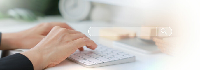 Hands typing on a white keyboard with search bar overlay, representing internet browsing, SEO, online research, digital marketing, communication, data input, coding and information search concept.