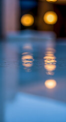 Soft reflections shimmer on a cool surface, creating a serene and calming ambiance with blurred light spots and blue hues.