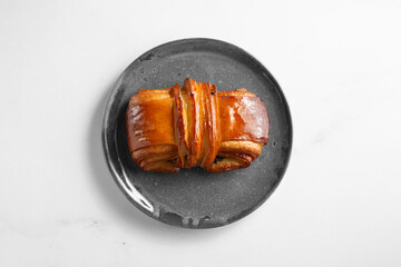 A top down view of a pain suisse pastry, on a plate.