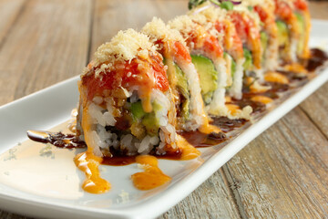 A view of an eel tempura roll, topped with spicy tuna.
