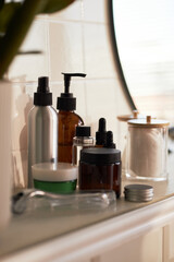 Assortment of skincare products including pump bottles, dropper bottles, jar, cotton pads and...