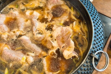 Beef sizzling sukiyaki pot ingredients in hot boiled soup. Top view