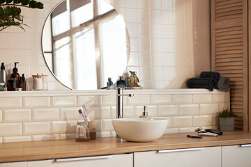Modern bathroom countertop featuring skincare products, soap dispenser, electric razor,...