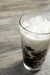 A view of a glass of grass jelly milk tea.