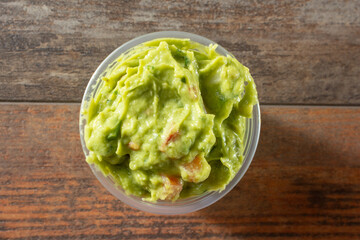 A top down view of a plastic condiment cup of guacamole.
