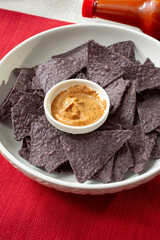 A view of a bowl of blue corn tortilla chips, with chipotle dip.