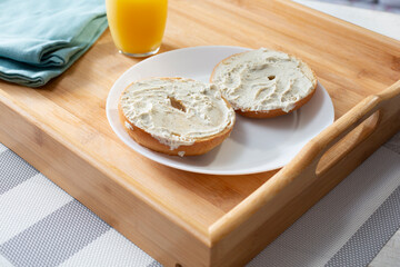 A view of a bed tray of gluten-free bagels, smeared with dairy-free cream cheese.