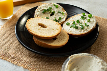 A view of a plate of gluten-free bagels, featuring dairy-free cream cheese and scallions.
