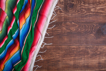 Colorful serape on wooden table. Typical colorful fabric from Mexico. Texture, background.