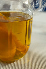 A closeup view of a mason jar filled with orange infused olive oil.