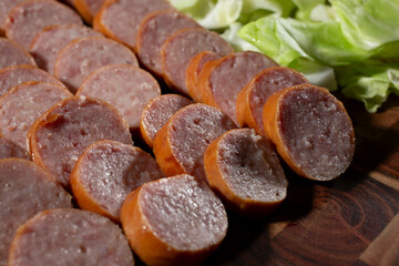 A view of sliced kielbasa on a wood board.