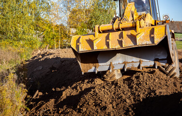 Yellow bulldozer at a construction site. Big wheel excavator leveling and clearing the land plot...