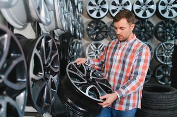 male customer choosing alloy wheel rims at car repair service or auto store